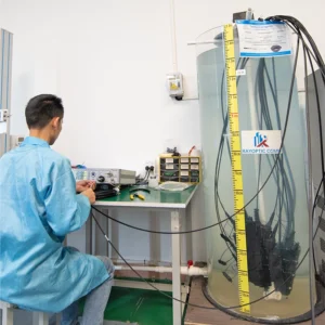 Rayoptic technician measuring insertion and return loss on a pre-connectorized MST and OptiTap flat drop cable after a 7-day, 1.5 m-deep water-immersion test in a cylindrical tank.